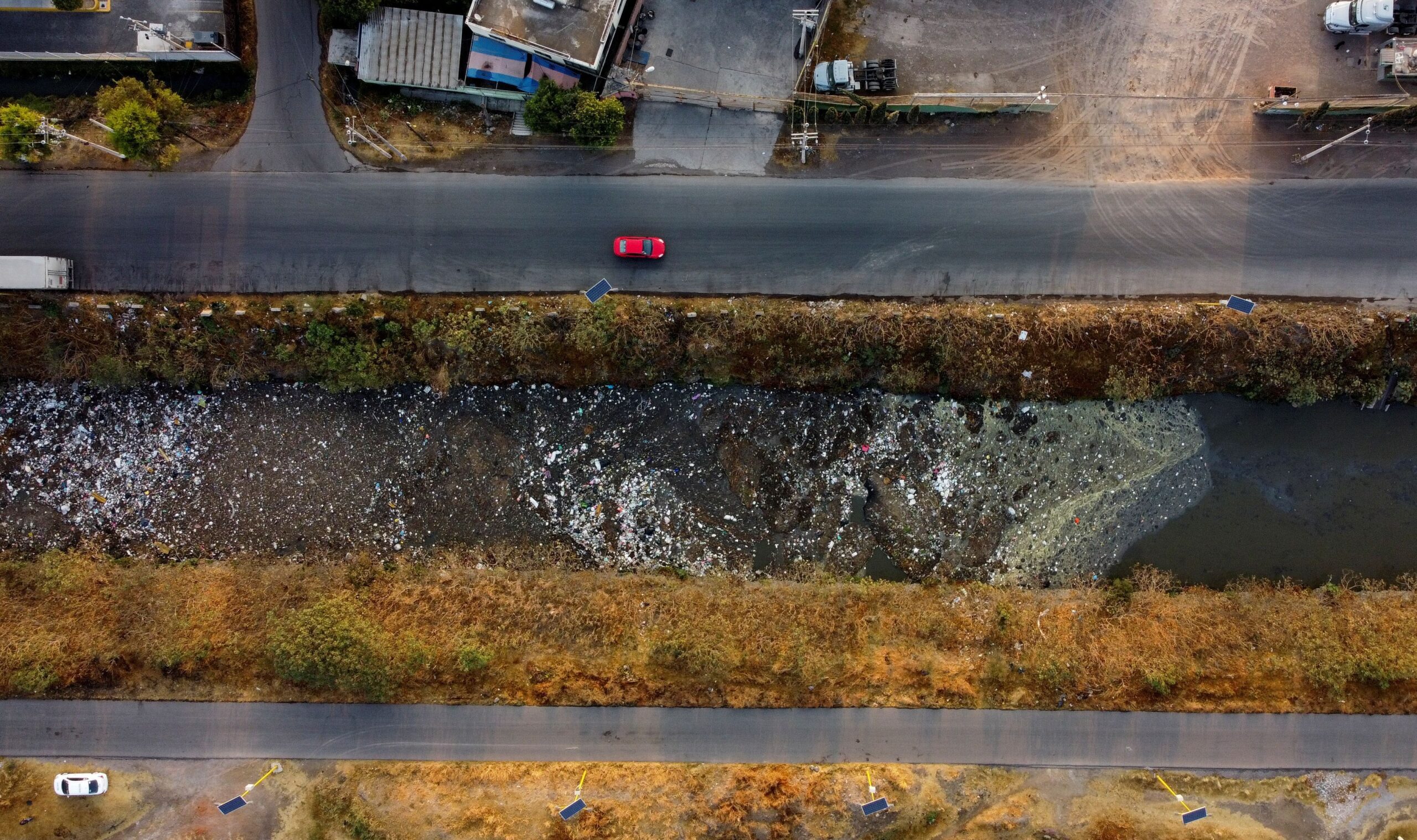Cars move next to the Interceptor Poniente canal in Cuautitlan, State of Mexico, Mexico, March 18, 2021. Drainage system waterways around densely-populated Mexico City are heavily polluted. REUTERS/Carlos Jasso