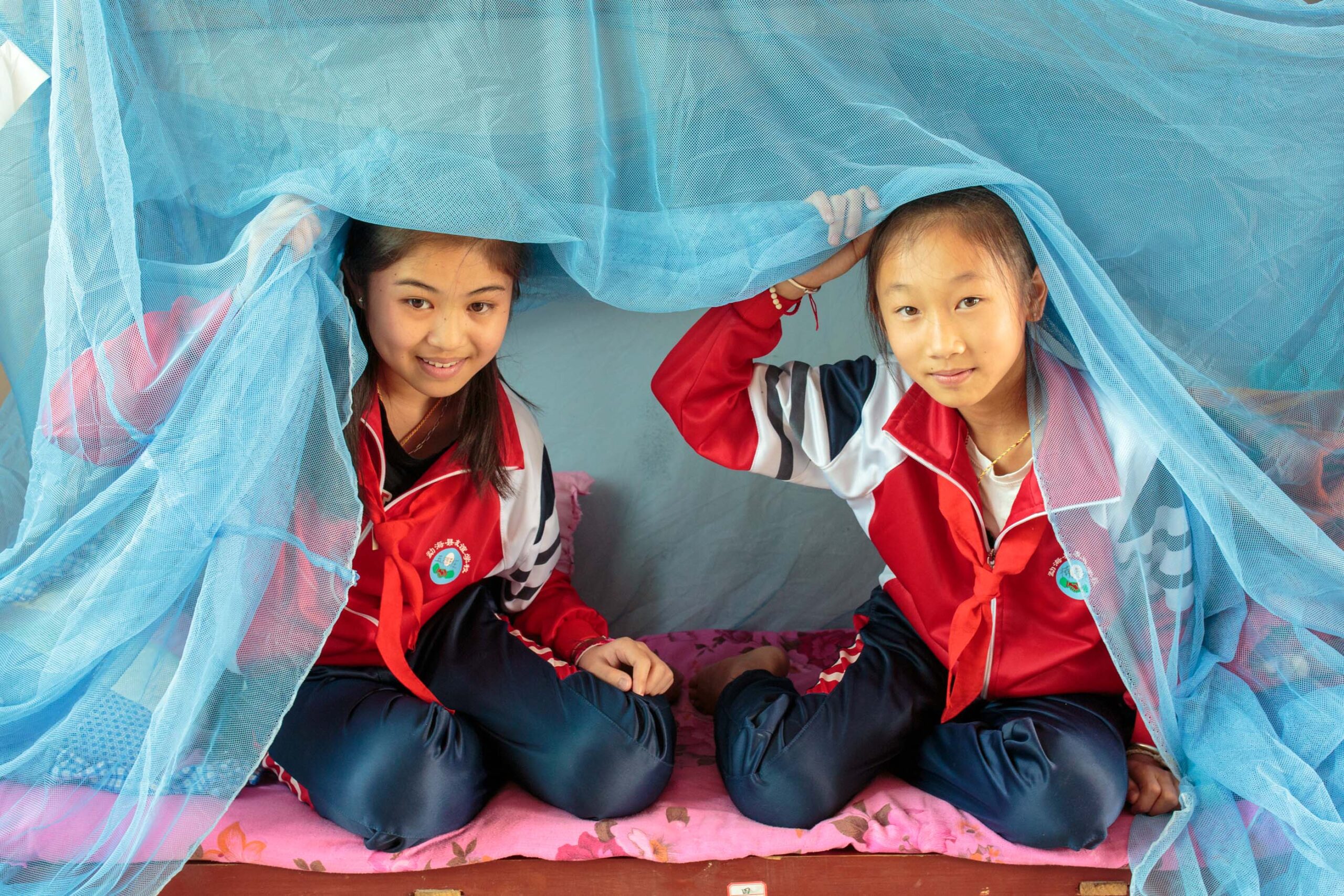 Nan Laodi, from Myanmar, and Huang Pei Pei, a Chinese student, use bed nets every night in their dorm room at the Friendship Primary School in Daluo, which is a few hundred metres from the Myanmar border. Meng Hai County, Yunnan Province. April 2019.