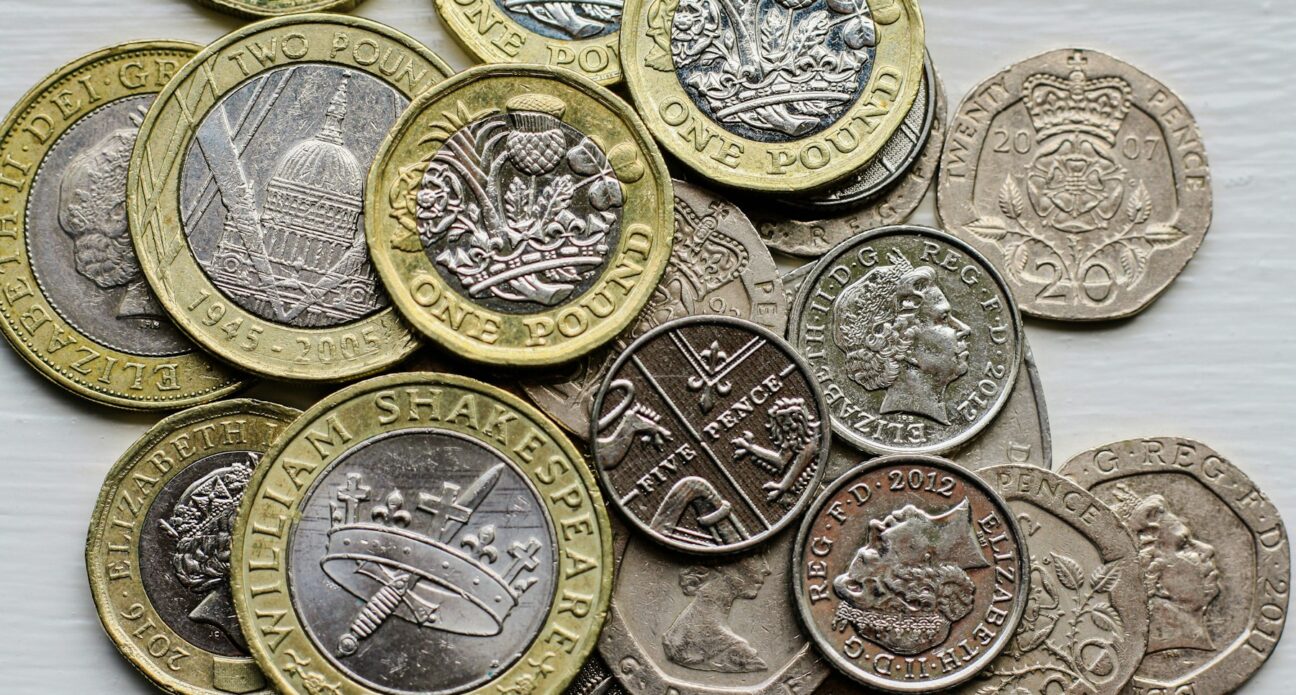 Pile of British pound, twenty pence and five pence coins on a table