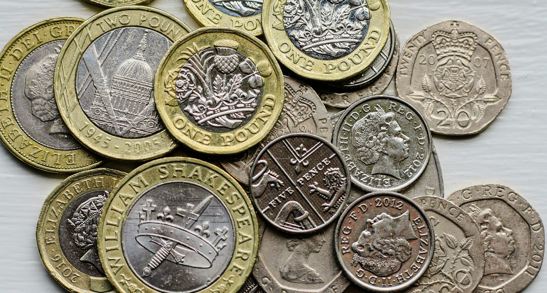 Pile of British pound, twenty pence and five pence coins on a table