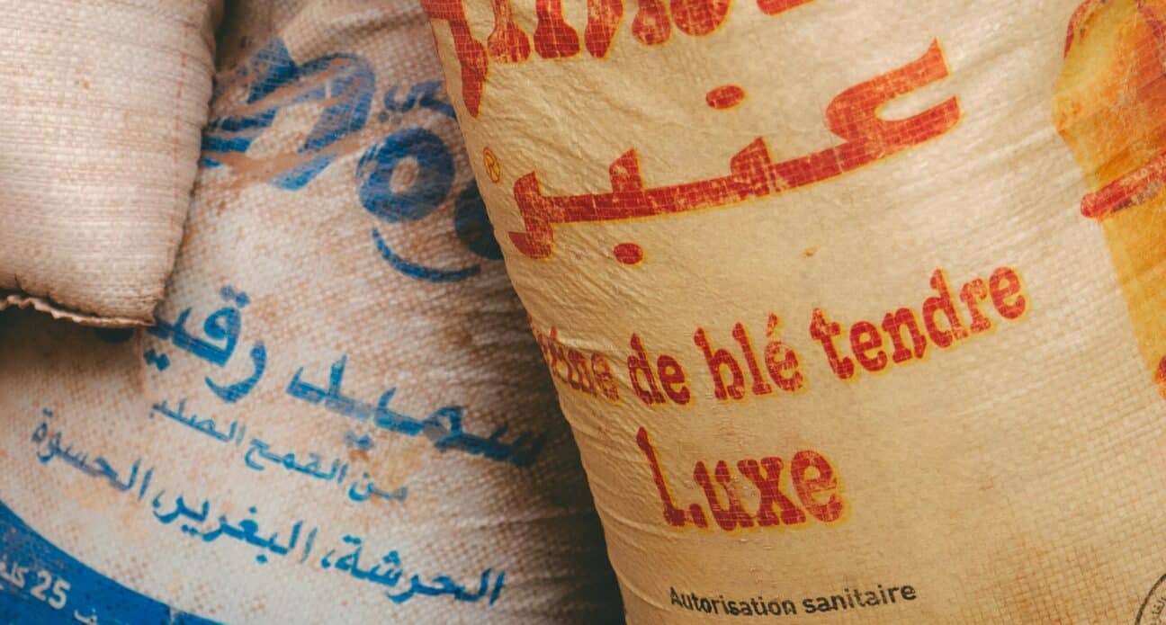 Sacks of flour with Arabic and French labels stacked for distribution